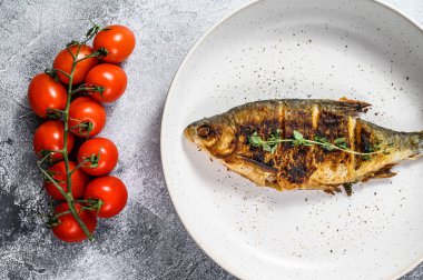 Beyaz tabakta ızgara sazan balığı. Nehir organik balığı. Gri arka plan. Üst görünüm.