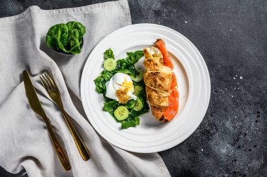 Somon ve ricotta peynirli kruvasan, ıspanaklı ve yumurtalı salata. Arka plan. Üst görünüm.