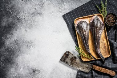 Ahşap tepside başı olmayan satırla birlikte taze bir maymun balığı. Gri arka plan. Üst Manzara. Boşluğu kopyala.