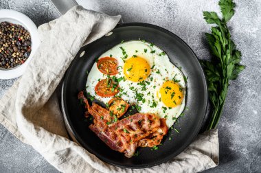 İngiliz kahvaltısı. Yağda yumurta, domates, pastırma. Gri arka plan. Üst görünüm.