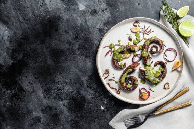 Pesto, kekik ve soğanlı ızgara ahtapot dokunaçları. Taze deniz ürünleri. Siyah arka plan. Üst Manzara. Boşluğu kopyala.