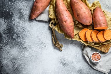 Doğrama tahtasında çiğ patates, organik yer elması. Çiftlik sebzeleri. Gri arka plan. Metin için boşluk.