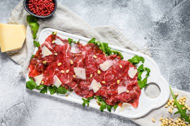 Mermer etli Carpaccio. Çiğ et, siyah Angus. Gri arka plan. Üst görünüm.