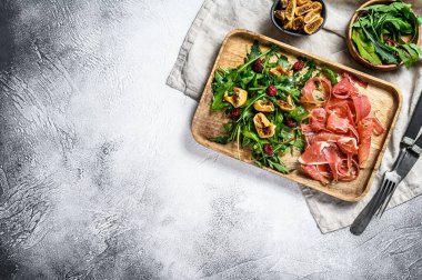 Parmalı salata, jambon, roka ve incir. İtalyan pastası. Gri arkaplan, üst görünüm, metin için boşluk.