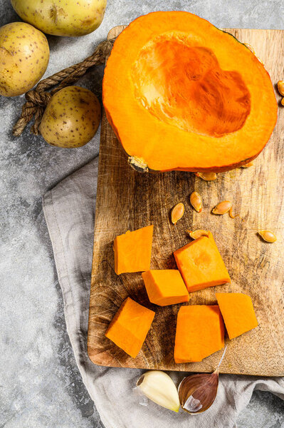 Ingredients for pumpkin soup. Pumpkin pieces on a cutting Board. Cream soup. Gray background. Vegetarian cuisine.