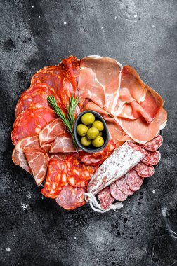 İspanyol soğuk et çeşitleri. Chorizo, fuet, LOMO, jamon Iberico, zeytin. Siyah arka plan. Üst görünüm