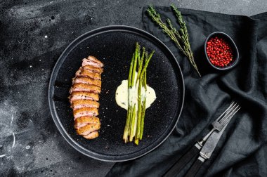 Kuşkonmaz, bitki ve baharatlı ördek filetosu. Siyah arka plan. Üst görünüm.