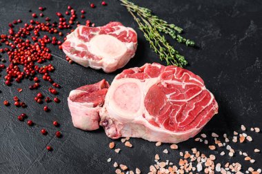 Çiğ taze ossobuco con ve şifalı otlar. Osso Buco eti. Siyah arka plan. Üst görünüm.