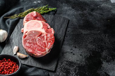 Baharatlı bir masada çiğ biftek ossobuco. Siyah arka plan. Üst Manzara. Boşluğu kopyala.