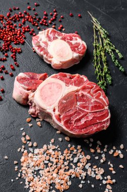 Çiğ dana şişi, Osso Buco baharat ve bitkilerle. OssoBuco eti. Siyah arka plan. Üst görünüm.