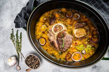 Çapraz kesilmiş dana bacağından yapılmış ossobuco ile demir tava. Ossobuco et yahnisi. Gri arka plan. Üst görünüm.