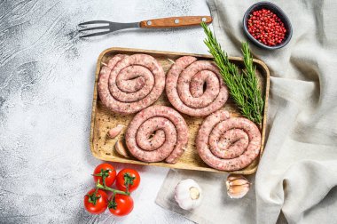Tahta tepside taze çiğ domuz sosisi. Gri arka plan. Üst görünüm.