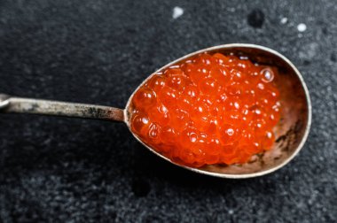 Lezzetli bir kaşıkta somon kırmızısı havyar. Siyah arka plan. Üst görünüm.
