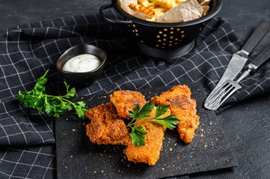 Balık ve patates kızartması, patates kızartması ve kızarmış balık filetosu. Siyah arka plan. Üst görünüm.