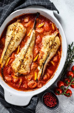 Fırın kabında domatesli maymunbalığı pişirmek. Taze deniz ürünleri. Gri arka plan. Üst görünüm.