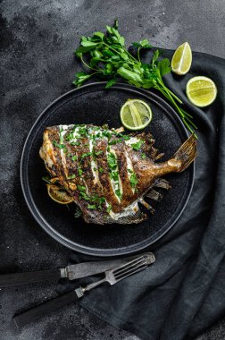 Limonlu ve maydanozlu ızgara John Dory balığı. Siyah arka plan. Üst görünüm.