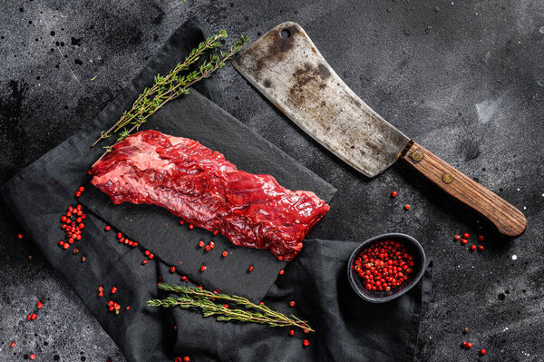 Raw skirt, machete steak with pink pepper and thyme. Black background. Top view.