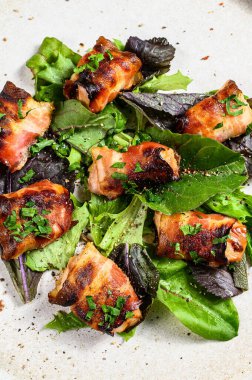 Domuz pastırmasına sarılı fırında tavuk göğsü ile yeşil salata. Gri arka plan. Üst görünüm.