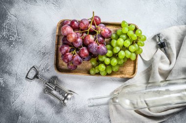 Şarap arka planı. Bir dal yeşil ve kırmızı üzüm, boş bir şişe, bir tirbuşon ve bir mantar. Ev yapımı şarap kavramı. Beyaz arka plan. Üst görünüm.