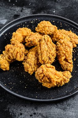 Siyah tabakta kızarmış tavuk kanadı. Siyah arka plan. Üst görünüm.