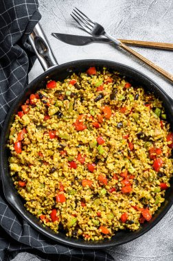 Sebze ve tavada tavuk etiyle pişirilmiş bulgur. Gri arka plan. Üst görünüm.