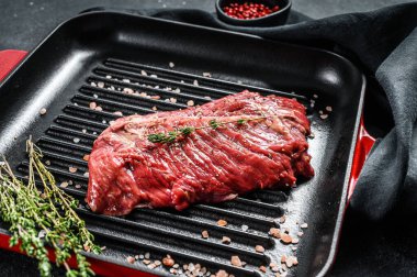 Izgara tavasında çiğ mermer biftek. Siyah arka plan. Üst görünüm.