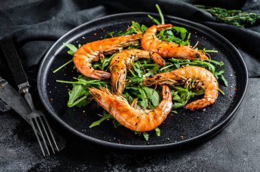 Izgara dev karides, karides, roka ve baharat. Siyah arka plan. Üst görünüm.