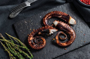 Kekik ve pembe biberli kızarmış ahtapot dokunaçları. Taze deniz ürünleri. Siyah arka plan. Üst görünüm.