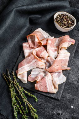 Biber ve kekik ile taze domuz pastırması dilimleri. Organik çiğ et. Siyah arka plan. Üst görünüm.