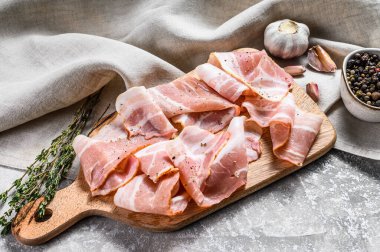 Doğrama tahtasında taze domuz pastırması. Organik çiğ domuz eti. Gri arka plan. Üst görünüm