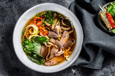 Geleneksel Vietnam çorbası Pho bo, bitkiler, et, pirinç eriştesi, et suyu. Siyah arka plan. Üst görünüm.