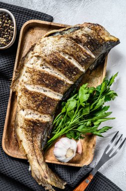 Kesme tahtasında bütün balık mezgit balığı pişirdim. Gri arka plan. Üst görünüm.