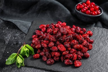 Kırmızı kurutulmuş kızılcık ve taze nane yaprakları. Organik çilek. Siyah arka plan. Üst görünüm