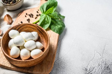 Tahta bir kasede fesleğen yapraklı mini mozzarella peyniri. gri arka plan. Üst Manzara. Boşluğu kopyala.