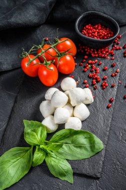 Mini mozzarella peyniri, fesleğen yaprağı ve vişneli domates, Caprese salatası. Siyah arka plan. en üstteki görünüm.