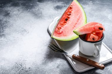 Beyaz bir kesme tahtasında olgun karpuz dilimleri. Gri arka plan. Metin için boşluk.