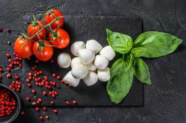 Caprese salatası, mini mozzarella peyniri, fesleğen yaprağı ve vişneli domates. Siyah arka plan. en üstteki görünüm.