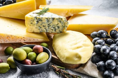 Fındık zeytinli ve üzümlü farklı peynir parçaları. Çeşit çeşit lezzetli atıştırmalıklar. Gri arka plan. Üst görünüm.