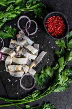 Salamura ringa fileto biber, otlar ve kırmızı soğanlı. Siyah arka plan. Üst görünüm.