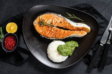 Pirinç ve ıspanakla süslenmiş ızgara somon bifteği. Siyah arka plan. Üst görünüm.