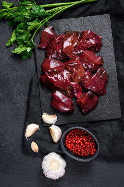 Taş tahtada çiğ tavuk ciğeri. Siyah arka plan. Üst görünüm.