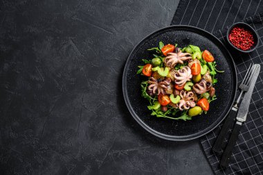 Izgara ahtapot, patates, roka, domates ve zeytinli salata. Siyah arka plan. Üst Manzara. Metin için boşluk.