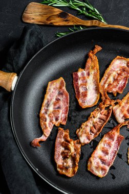 Kızarmış domuz pastırması dilimleri. Çiftlik organik eti. Siyah arka plan. Üst görünüm.