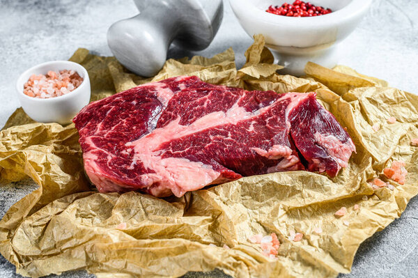 Raw marbled beef steak on a chopping Board. Organic farm meat black Angus. Gray background.