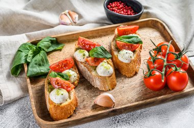 Domates, mozzarella peyniri ve fesleğen. İtalyan aperatifi ya da aperatifi, antipasto. gri arka plan. en üstteki görünüm.