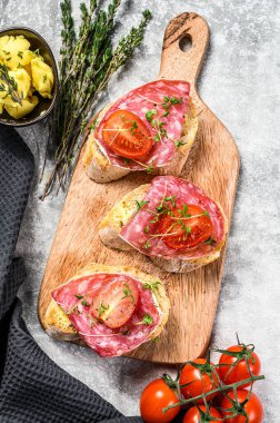 Salam salçalı sandviç, kiraz domatesli ve mikro yeşillikli. gri arka plan. en üstteki görünüm.