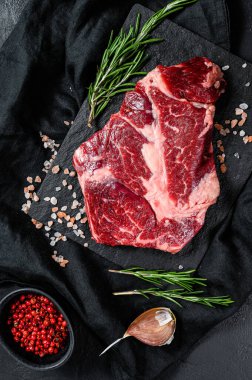 Doğrama tahtasında çiğ biftek. Organik çiftlik eti. Siyah arkaplan.