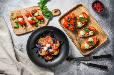Çeşit çeşit Caprese salatası, şiş, kanepe, kiraz domatesli bruschettes, mozzarella ve Basil. gri arka plan. en üstteki görünüm.