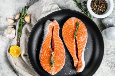 Kızartma tavasında çiğ somon bifteği. Sağlıklı deniz ürünleri. Gri arka plan. Üst görünüm.