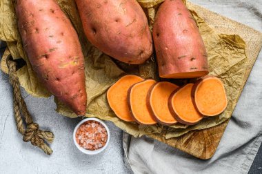 Doğrama tahtasında çiğ patates, organik yer elması. Çiftlik sebzeleri. Gri arkaplan.